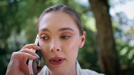retrato de una chica insatisfecha llamando por teléfono de pie en el parque. mujer hablando por teléfono inteligente