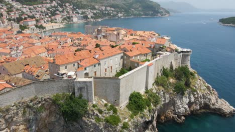 aerial drone forwarding shot over the old fortress wall along the old town of dubrovnik, croatia with the view of building rooftops on a sunny daytime