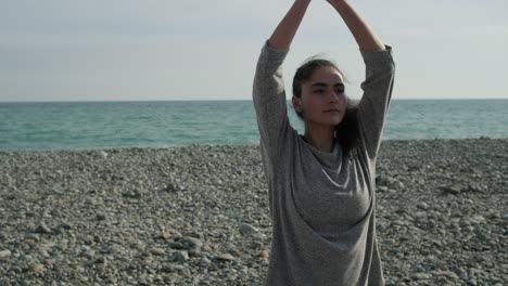 woman practicing yoga on a beach