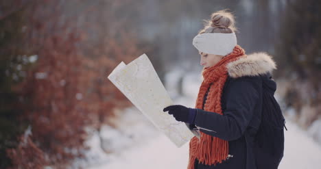 female tourist reading map in woods in winter