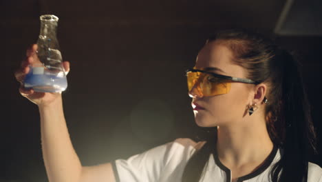 experiments in a chemistry lab. young woman scientist mixing reagents from glass flasks