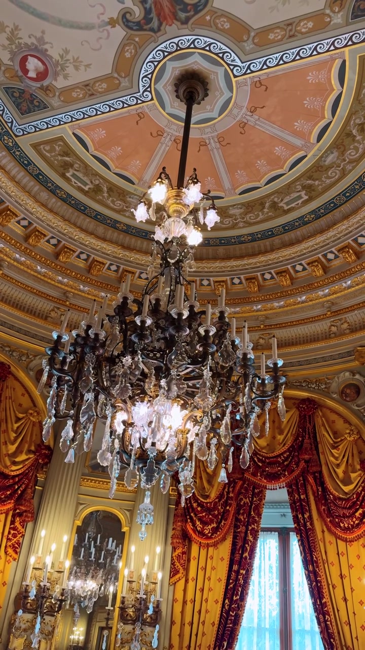 Boston, USA, 5 maggio 2025: Lampadario decorativo in cristallo appeso a un rosone circolare dipinto sul soffitto. Lampadario di cristallo contro un soffitto a cupola con dipinti classici e architettura dorata.