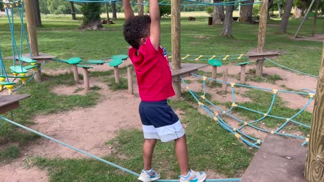 niño negro de 4 años jugando en un parque infantil en un patio de recreo en el bosque
