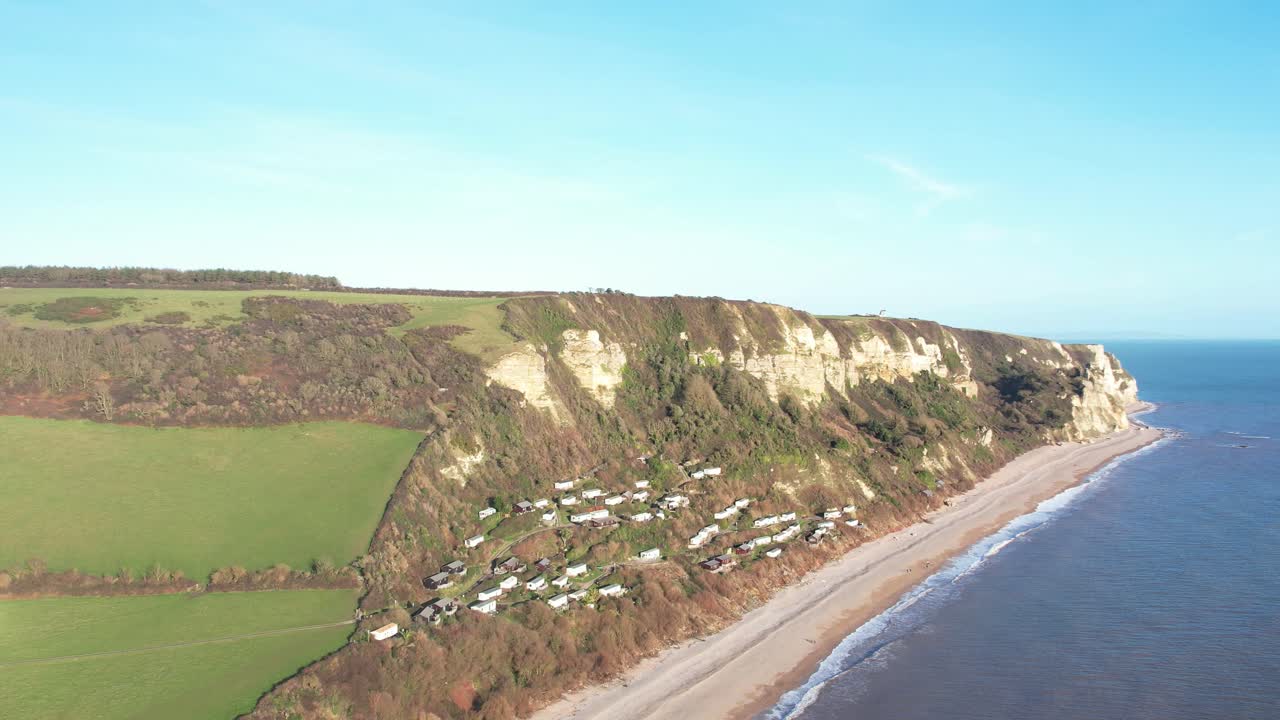 Aerial view of Branscombe village with its holiday homes nestled on a picturesque hillside next to the Devon coastline in England. Orbit Motion