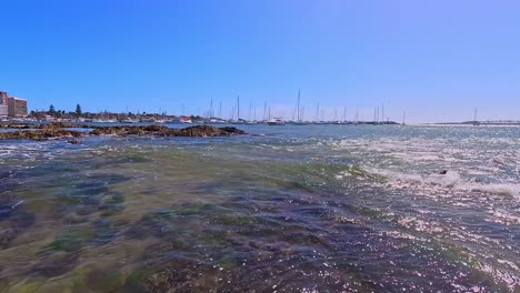 Video-moving-from-below-to-above-water,-showing-crashing-waves-and-the-Punta-del-Este-harbour,-Uruguay