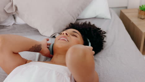 black woman, headphones and on bed listen to