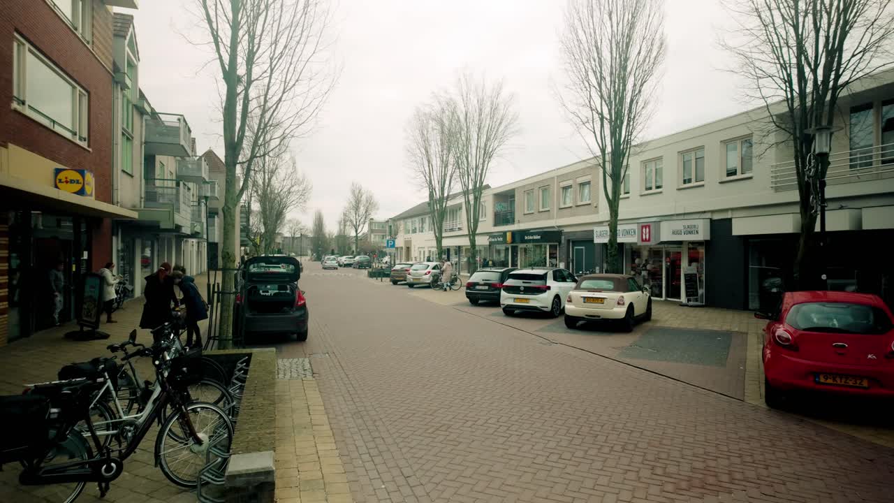 A street scene with cars, shops, and people.