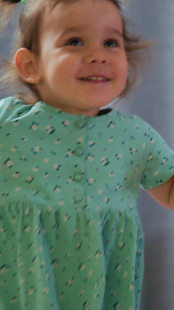 A Joyful Moment Captured: A Young Child in a Green Outfit Radiating Happiness and Energy in a Home Environment