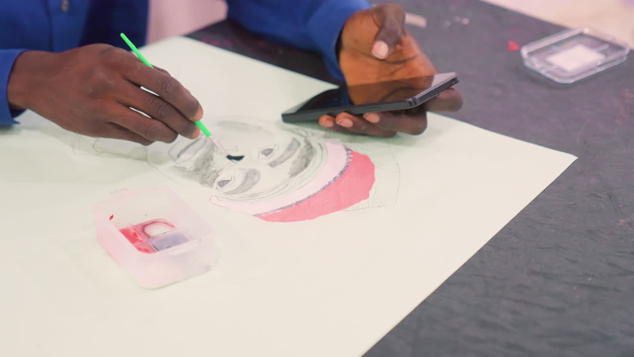 Black artist painting portrait with phone, mobile reference and wider studio view, hand holding phone while brush adds gray tones and pink wash, plastic paint tray, freelance commission vibe, modern