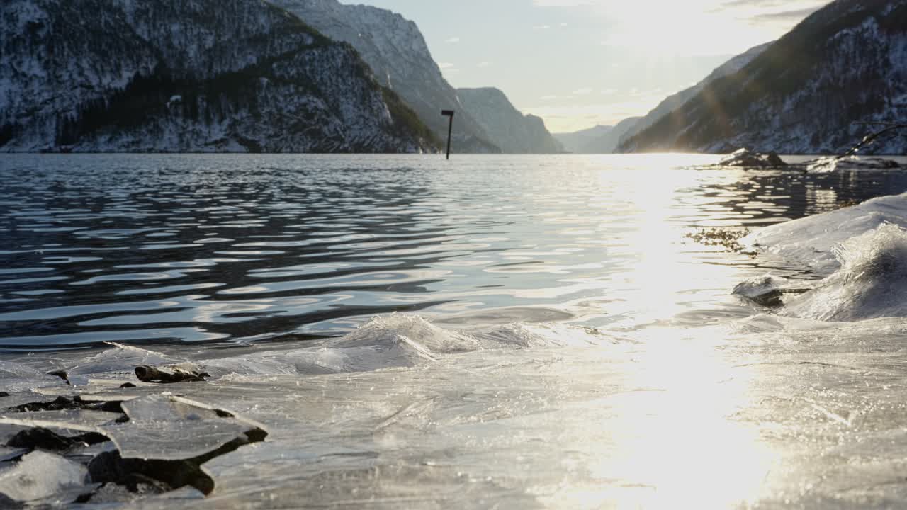 Stunning Veafjord in Norway with a golden winter sun reflecting on rippled water. Frozen fjord ice in the foreground, showcasing untouched nature