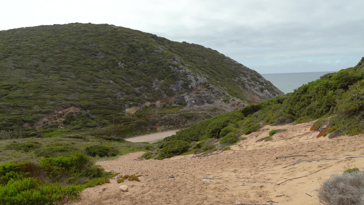 playa de arena cerca de la colina gruta da adraga en un día nublado en portugal