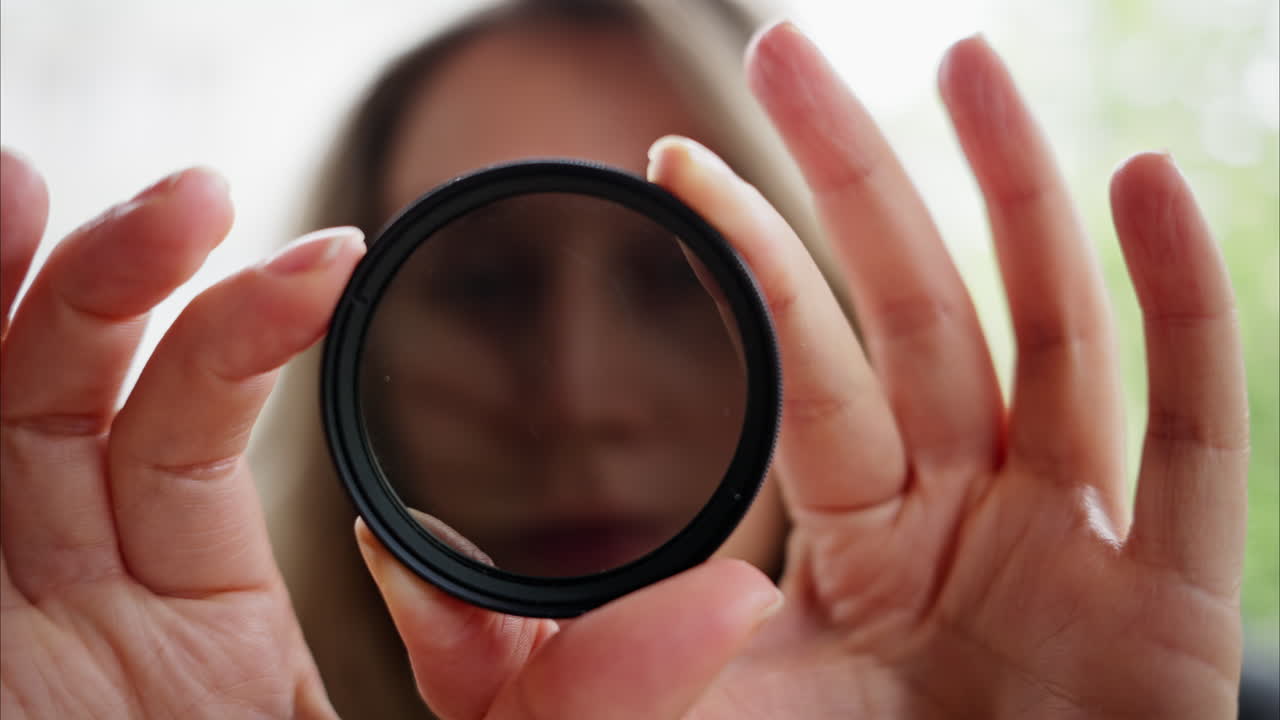 Woman looking through camera lens neutral density nd filter while rotating it