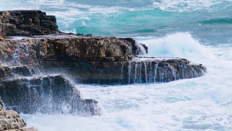 Sea-waves-breaking-on-rocky-shore-creating-foam-and-mist-on-stormy-weather---medium