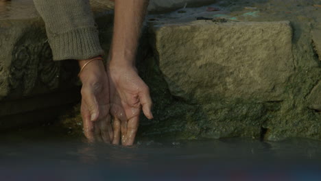 a man splashes his hands in a river