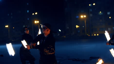 man and woman in black costumes and dark make up showing the fire spectacle. actors present fire show.