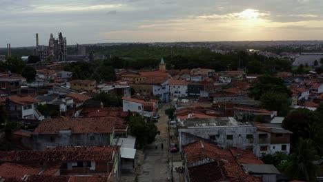 Rising-aerial-drone-shot-of-a-small-historic-neighborhood-road-in-the-old-downtown-of-the-tropical-coastal-capital-city-of-Joao-Pessoa,-Paraiba,-Brazil-with-homes,-churches-and-factories-during-sunset
