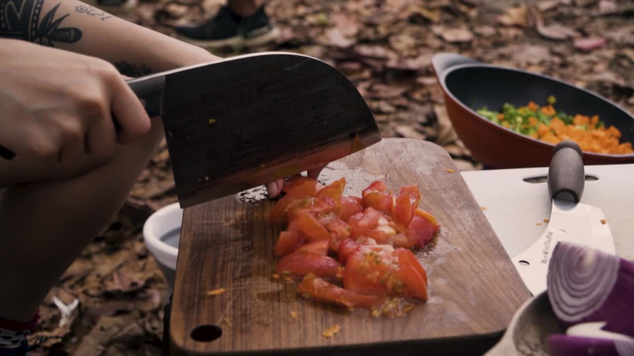싱가포르 풀라우 우빈에서 캠핑을 하는 동안 나무 도마에 토마토를 썰고 있습니다.