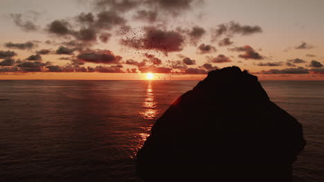 sunset over a rock formation with birds