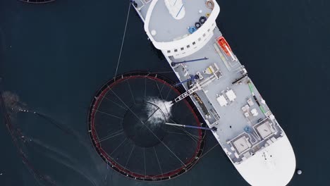 Disparo-De-Un-Dron-Sobre-Un-Barco-De-Cultivo-De-Peces-Mientras-Arroja-Peces-A-Una-Jaula