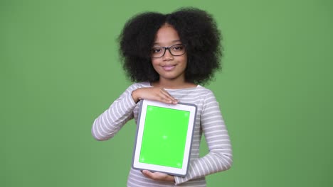 una joven africana con cabello afro mostrando una tableta digital a la cámara