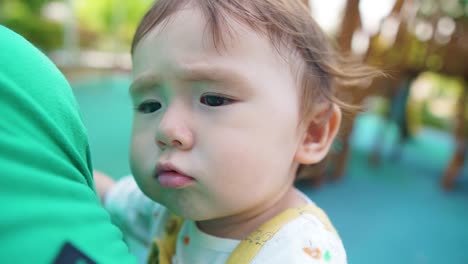 cute little baby girl sitting on father's hand and leaning on shoulder daytime slow-motion, face expression close-up