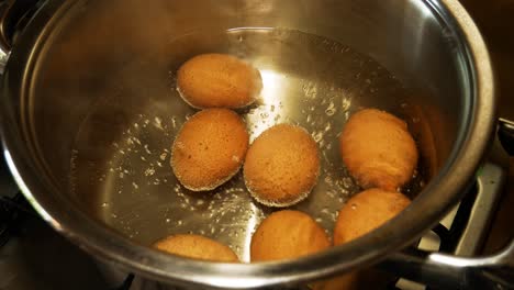 boiling eggs in steel pot with one egg crackled