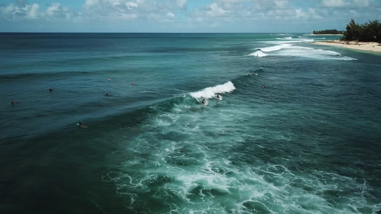 Drone shot of two surfers catching a wave on the North Shore coast of Oahu, Hawaii