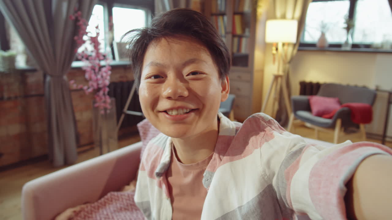 긍정적 인 아시아 여성이 집에서 비디오 통화로 채팅합니다.