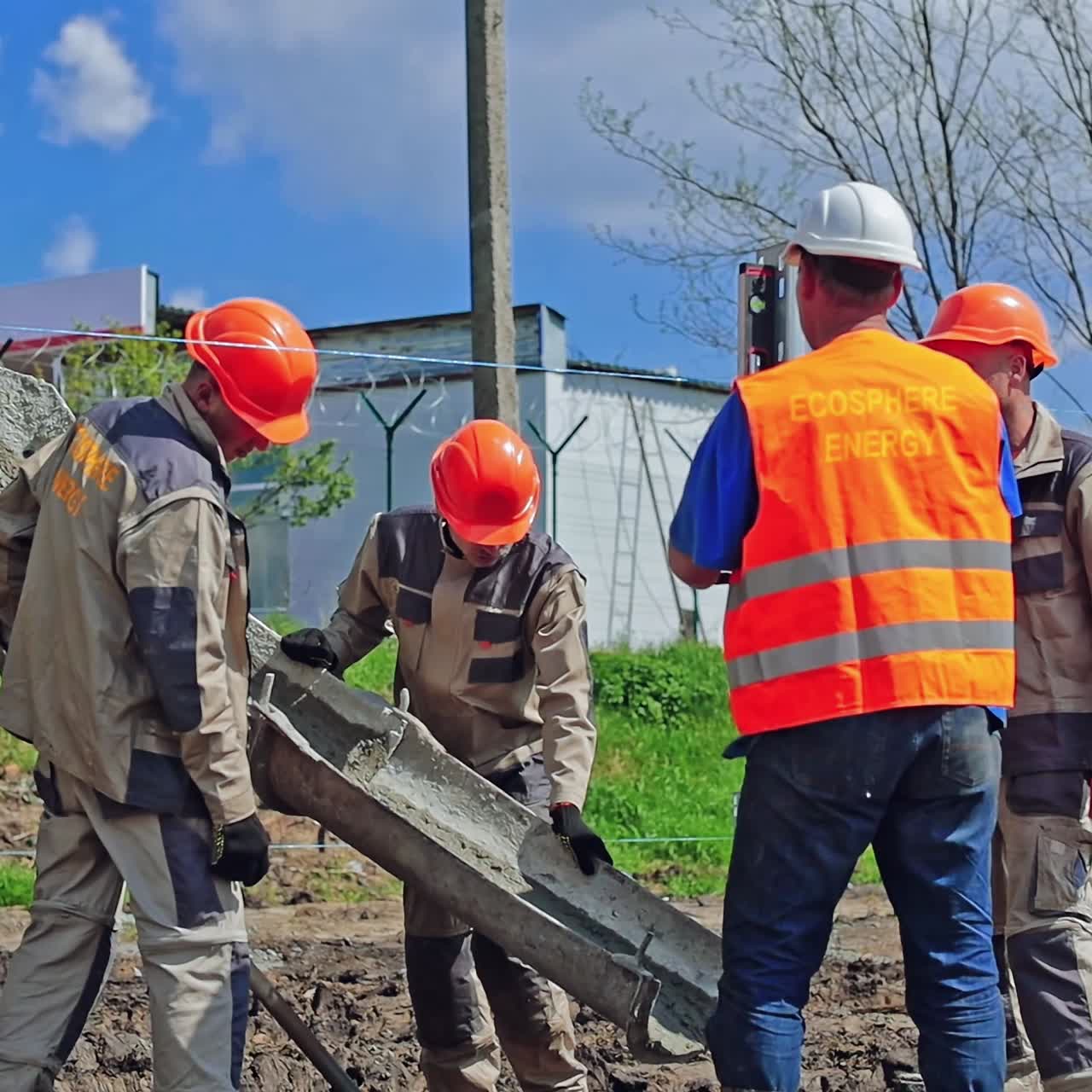 Group of workers installing metal base. Industrial machine with cement. Workers put metal construction before installing solar panels on the ground.