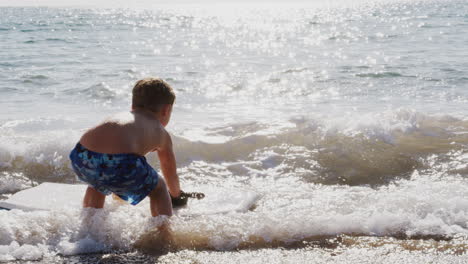 boy playing in sea with bodyboard on  summer beach vacation