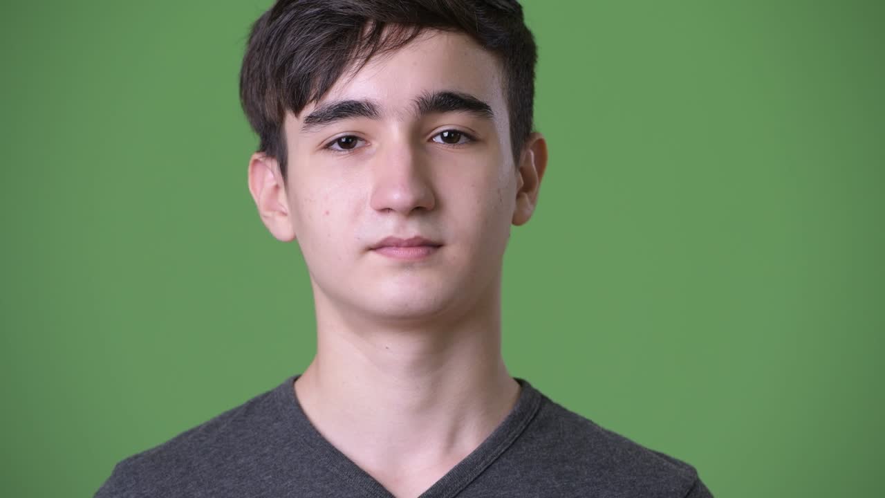 joven y guapo adolescente iraní contra un fondo verde