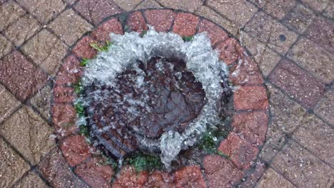 gushing water through manhole on wet pavement after rainstorm