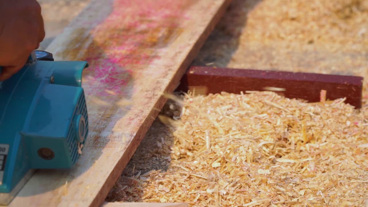 carpintero que trabaja usando una máquina de planchar para suavizar la tabla