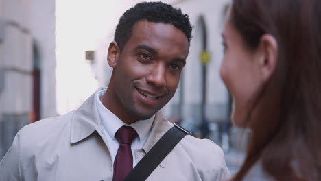 millennial black businessman standing in the street listening his white female colleague talking, close up, selective focus