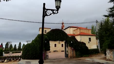 Entrance-to-Santuario-Virgen-de-las-Vinas-covered-in-vegetation-with-street-lamp-in-foreground,-Spain