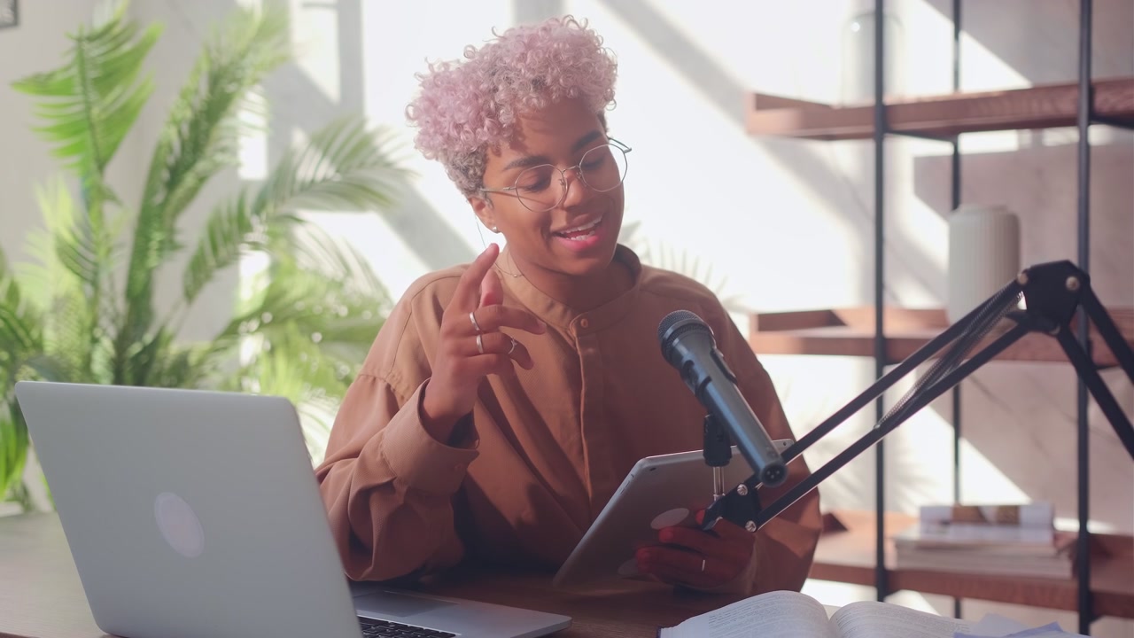Kvinde foran en mikrofon læser fra en digital tablet under en podcast.