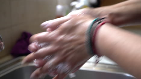 cerca de una mujer lavándose las manos con jabón líquido sobre el fregadero de una casa