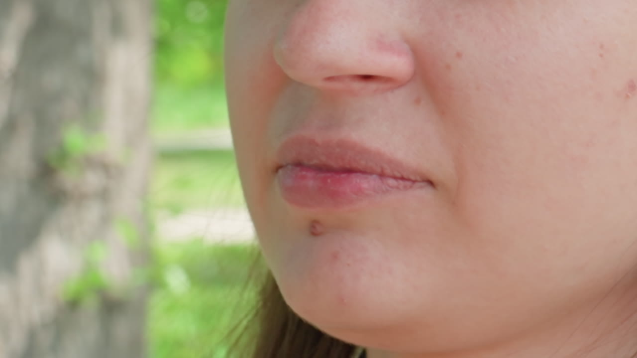 Donna che tossisce all'aperto, donna con problemi respiratori all'esterno, primo piano di donna che tossisce in un parco, donna che tossisce e mostra preoccupazione in un parco con sfondo naturale