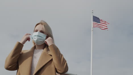 portrait of a woman in a protective mask against the background of american flag. 4k video