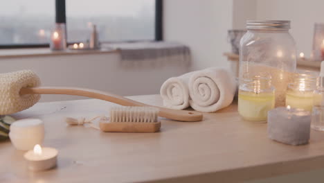 camera focuses on a white bathtub with water and wooden table with bathroom elements