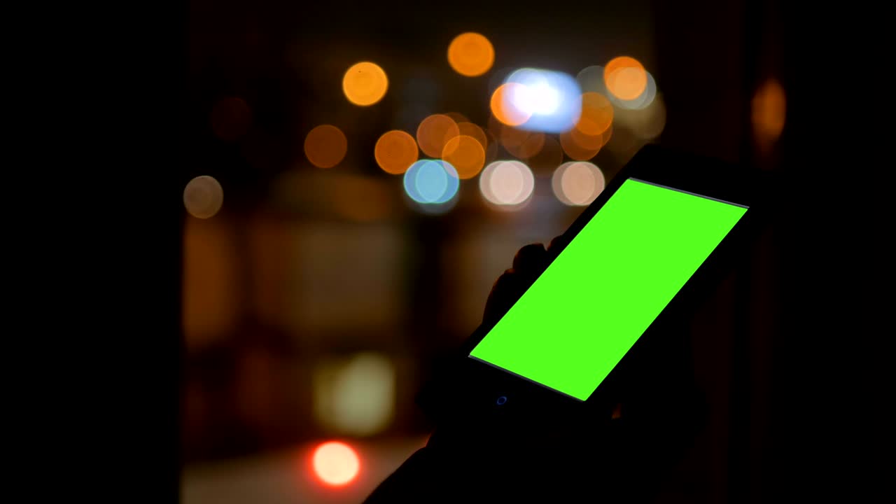 Woman looking at smartphone with green screen