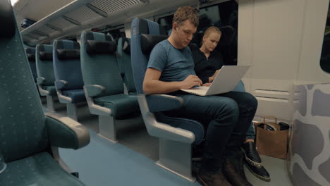 commuters with laptop and cell in train