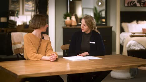 a female furniture sales person closes a deal with customer at a table