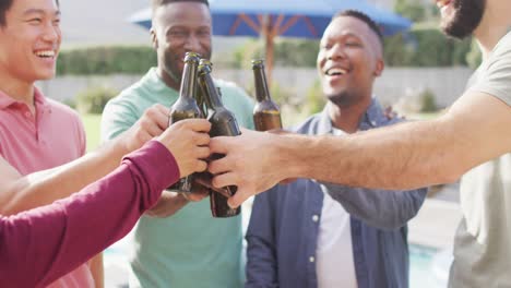 happy diverse male friends talking and drinking beer in garden on sunny day