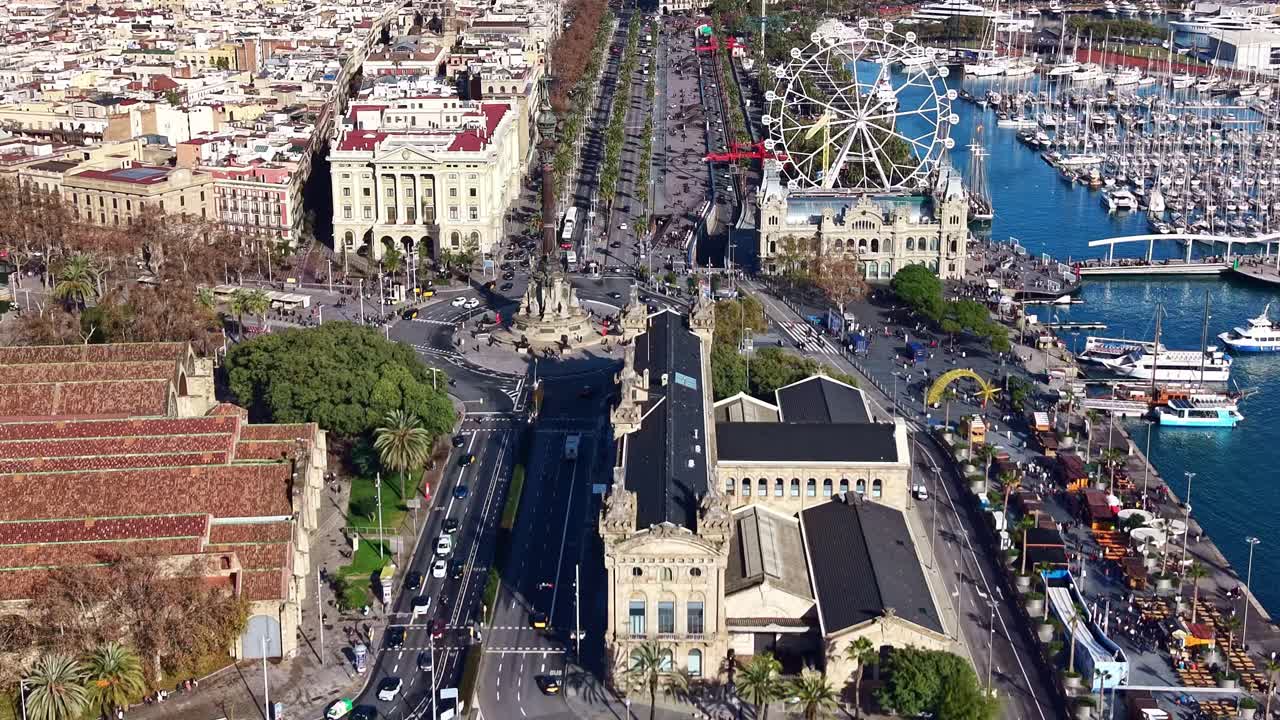 ランブラ通りの端にあるコロンブス記念碑を見下ろすドローンによる空撮。観覧車、ランブラ・デ・マール、そしてポートベルのマリーナ全体の景色が見えます。