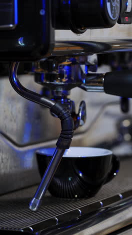 barista using coffee machine in cafe. young barista preparing coffee at automatic machine in modern coffee shop