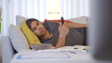 hombre perezoso aburrido acostado en el sofá y viendo televisión.
