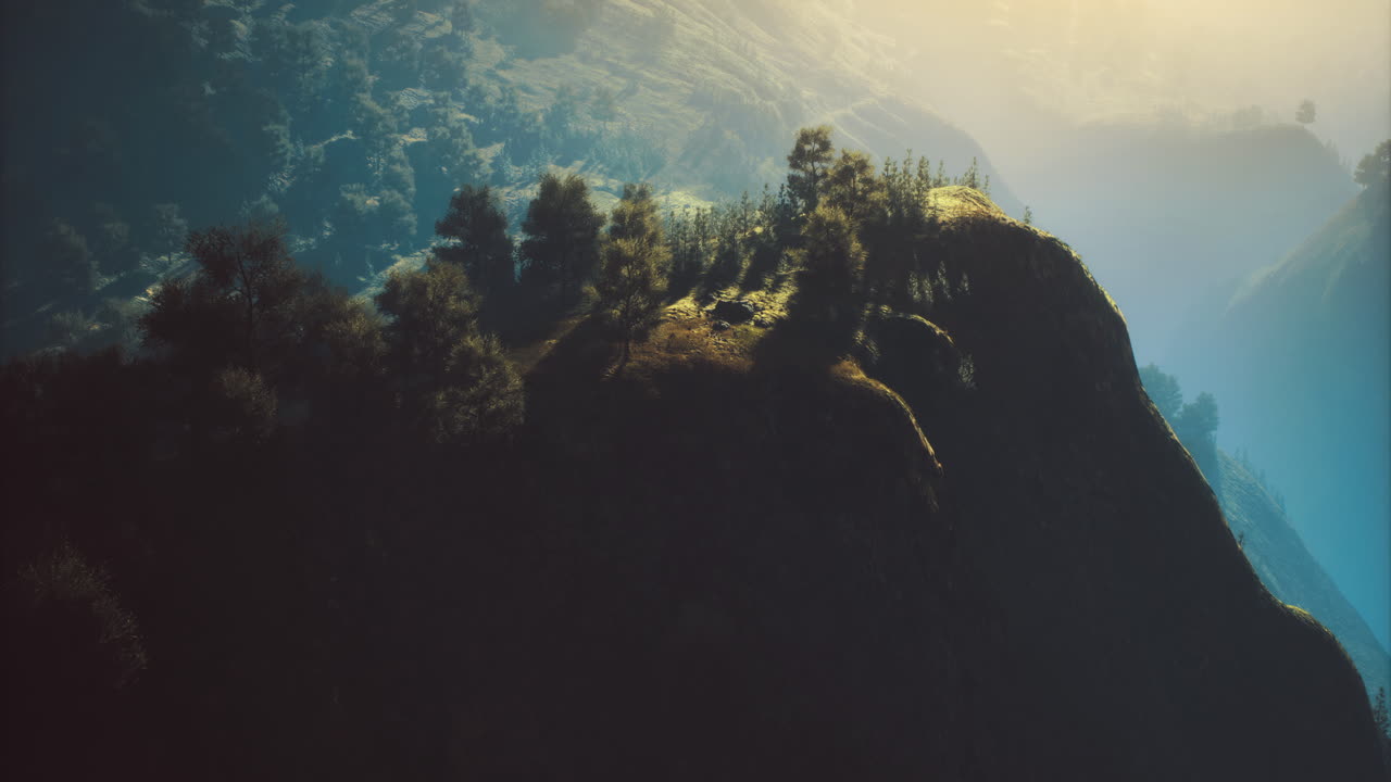 Mountain landscape featuring trees and sunlight at dawn in a distant valley