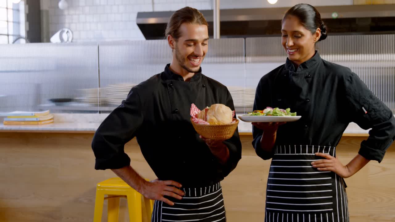 chefs sonrientes presentando su plato en la cocina comercial 4k