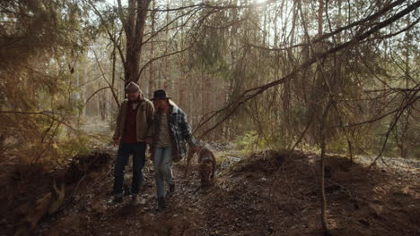 Couple-Holding-Hands-and-Walking-with-Dog-in-Woods